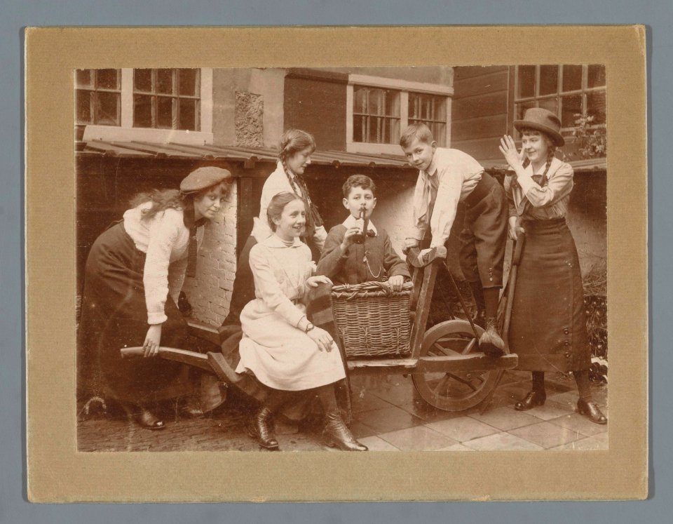 Groepsportret van Ad, Han en Johanna van der Kop en drie onbekende familieleden rond een kar in een tuin, RP-F-F20882