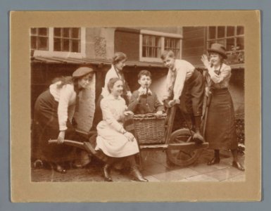 Groepsportret van Ad, Han en Johanna van der Kop en drie onbekende familieleden rond een kar in een tuin, RP-F-F20882