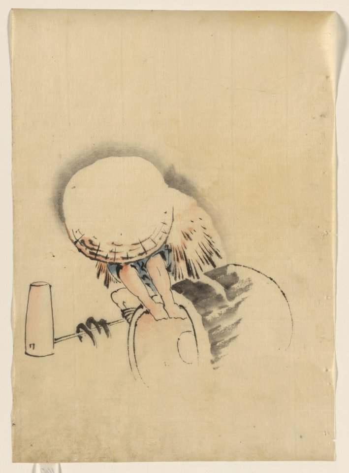 A man, wearing a large conical hat and a straw or feather garment, attempting to turn on end a barrel-like object, possibly a mochi tub; on the ground next to him is long-handled mallet LCCN2009631914