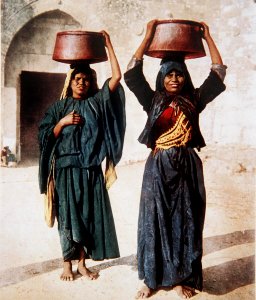 ARAB WOMEN IN JERUSALEM CARRYING CONTAINERS FILLED WITH LABANEH