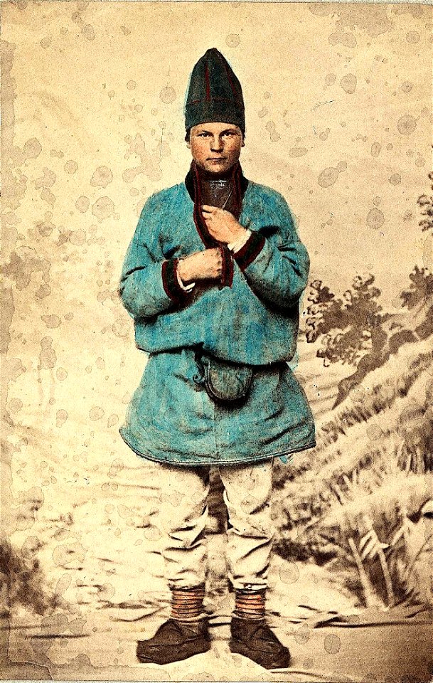 53. Mannsdrakt, samedrakt, Salten. Portrett av mann stående i fotoatelier foran malt naturbakgrunn - Norsk folkemuseum - NF.00690-004