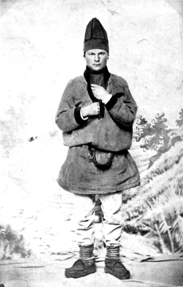 53. Mannsdrakt, samedrakt, Salten. Portrett av mann stående i fotoatelier foran malt naturbakgrunn - Norsk folkemuseum - NF.08676-004 (3)