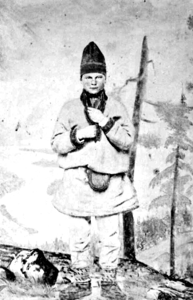 53. Mannsdrakt, samedrakt, Salten. Portrett av mann stående i fotoatelier foran malt naturbakgrunn - Norsk folkemuseum - NF.06145-014