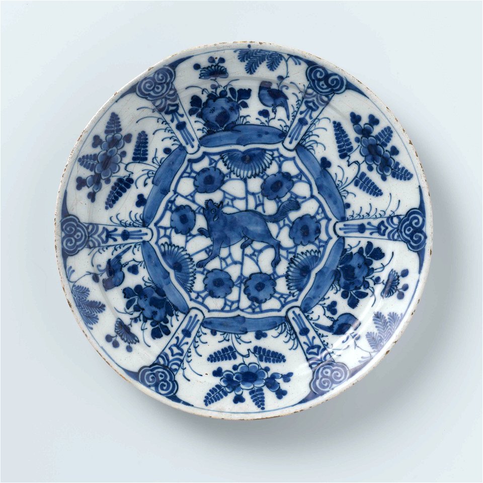 Bord van blauw en wit Delfts aardewerk, versierd met planten en vogels en een grommende wolf of vos in het midden