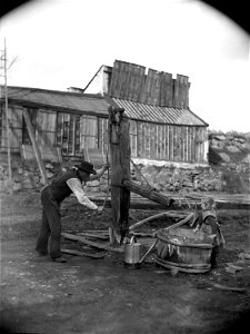 En man som pumpar vatten och en liten flicka vid en gammal pump. Ca 1880-1890. Eriksbergsområdet, Stockholm - Nordiska Museet - NMA.0052575