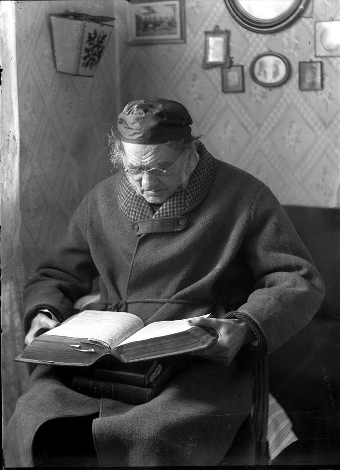 En äldre man sitter och läser en bok - Nordiska Museet - NMA.0052612