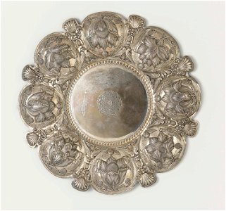Schaal van zilver, met acht lobben, afgewisseld door schelpen en vogels en kinderkopje. Drijfwerk van bloemen.