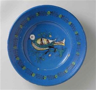 Schotel, veelkleurig beschilderd met op het plat een vogel op een tak. Randversiering van stippen en spiralen.