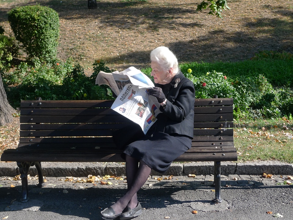 Park bench reading a newspaper elderly woman
