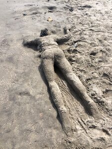 Person with sand face down on sand figure in the sand