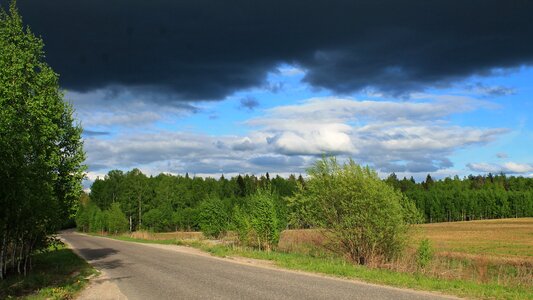 Blue sky clouds the road in the woods photo