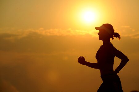 Silhouette of a young woman jogger at sunset on the seashore photo