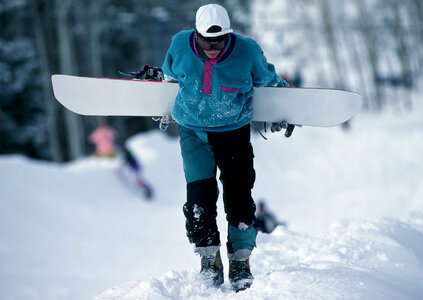 snowboarder walking against snowy mountains