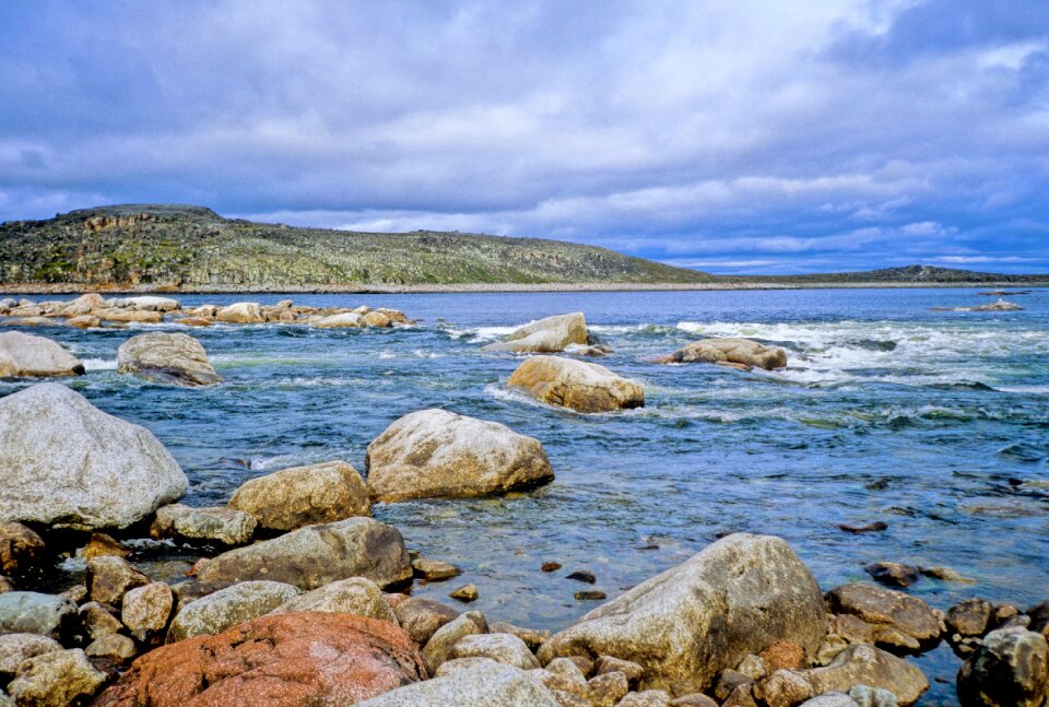 Clear river with rocks leads towards mountains