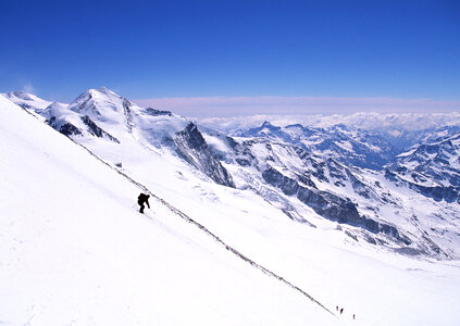 Alpine skier skiing downhill, blue sky on background