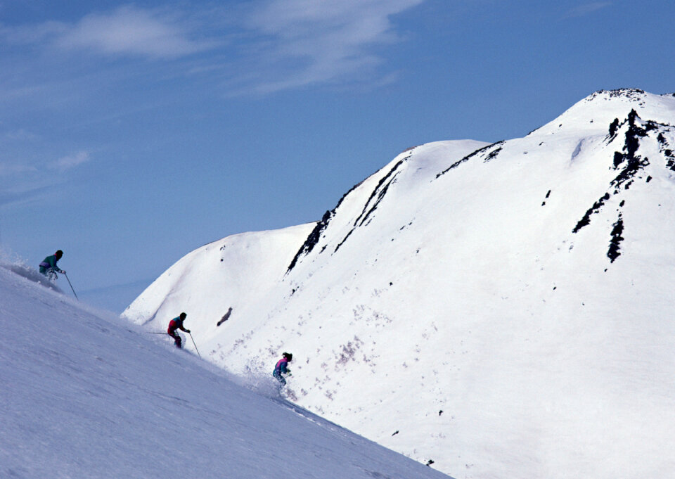 Alpine skier skiing downhill, blue sky on background