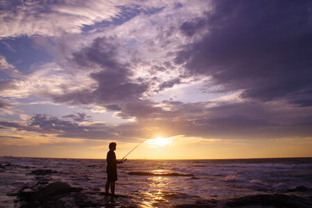 sunset fishing. fisher with spinning rod photo