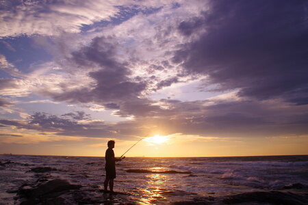 sunset fishing. fisher with spinning rod