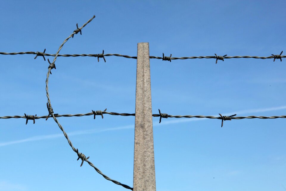 Barbed wire on fence with blue sky