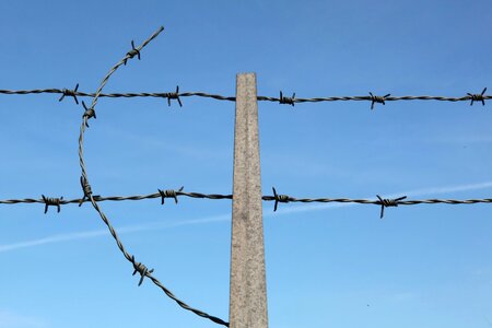 Barbed wire on fence with blue sky photo
