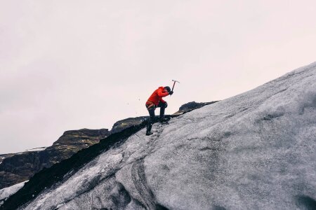 Climber ascending snowy peak at mountains photo