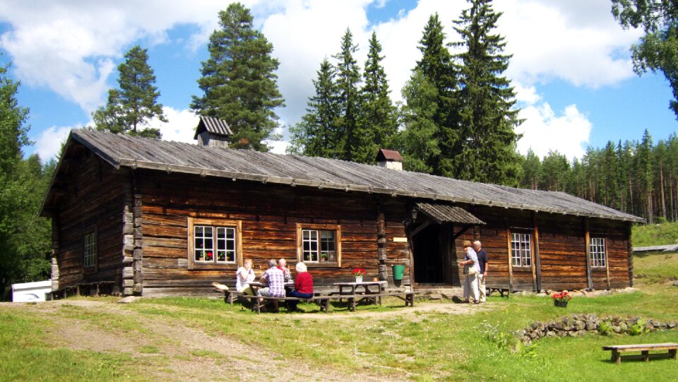 Cozy wooden cottage winter snow three people sitting outside