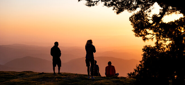 A group of people meet the sunrise at the peak of the mountain