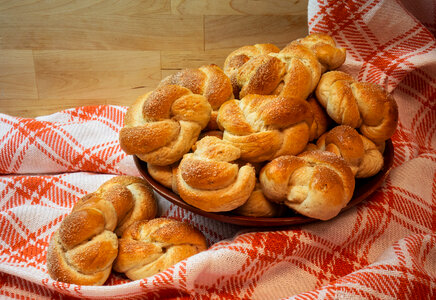 A wooden bowl of newly-baked cardamom buns on a checkered linen photo