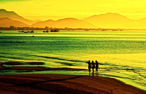 Women walk on the beach at sunset