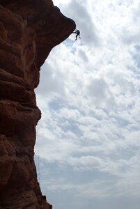 Young man climbing natural rocky wall photo