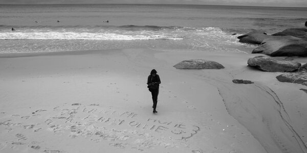 woman walking on sand beach leaving footprints in the sand photo