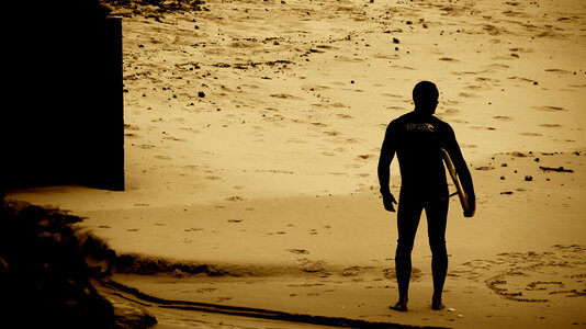 Sunset on the beach with surfer watching waves