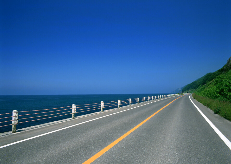 Turning mountain highway with blue sky and sea