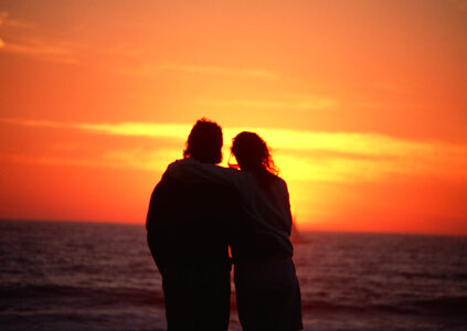 young happy couple at sunset beach photo