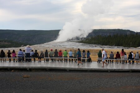 Tourists watching the Old Faithful erupting in Yellowstone photo