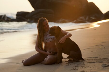 blond woman sitting on sand with dog photo