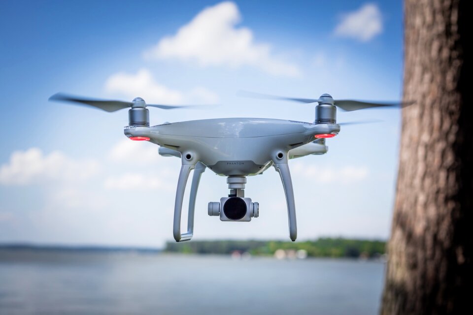 white drone hovering in a bright blue sky
