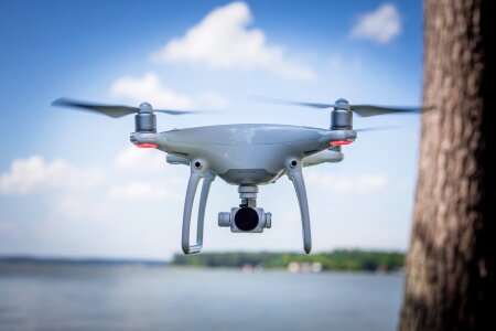 white drone hovering in a bright blue sky photo