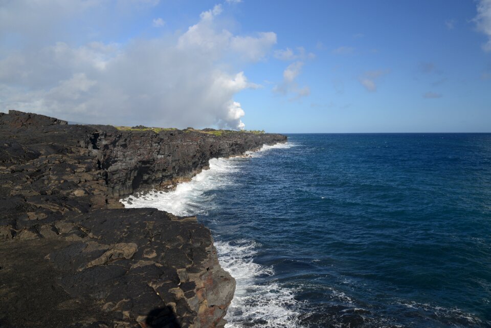 Waves crash along the black lava rock cliffs in the Hawaii