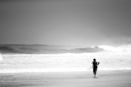 A man is walking with a surf in his hands across the sea shore photo