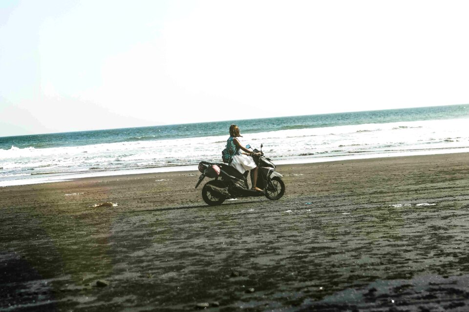 Young woman driving a scooter at the beach