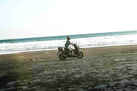 Young woman driving a scooter at the beach