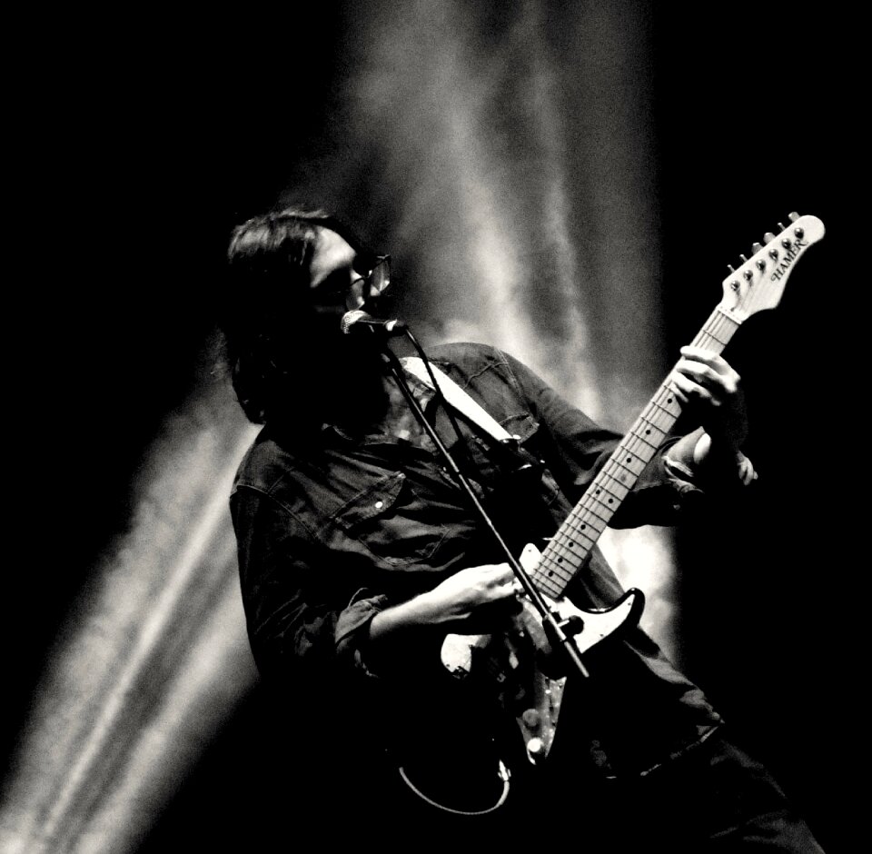 man playing electrical guitar in black and white photo