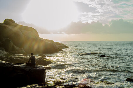 Man thinking while sitting on a rock photo