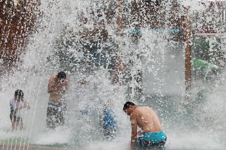 people playing in a water fountain photo