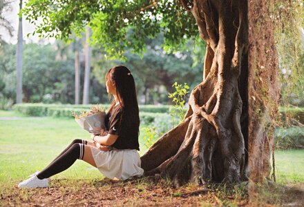 Beautiful young girl below the tree in the garden