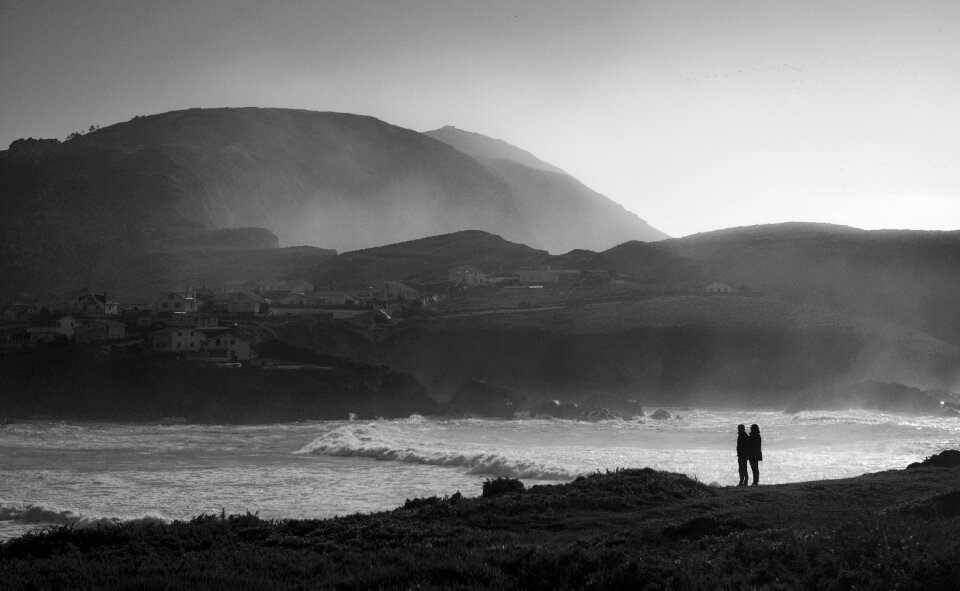 romantic couple standing on rocks by sea