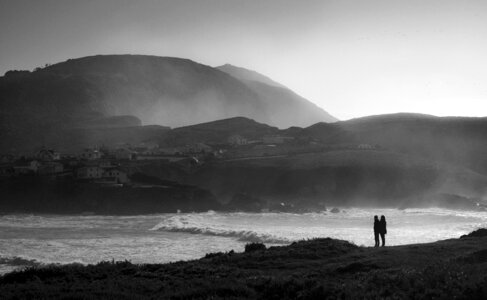 romantic couple standing on rocks by sea