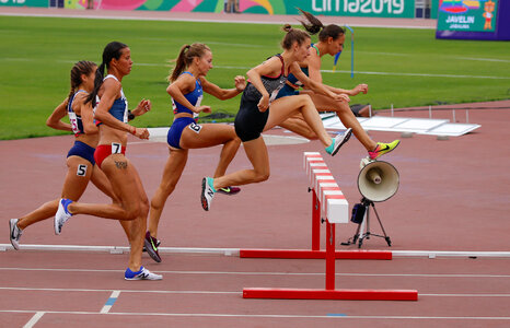 Female sprinter leaping over hurdles