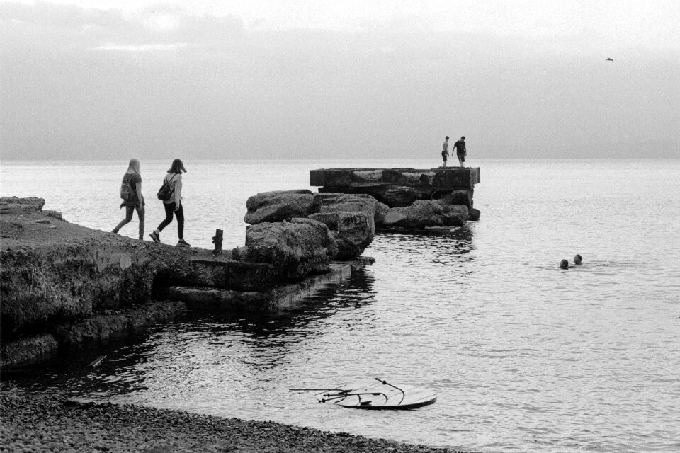 Black and white view of women walking together on rocky beach